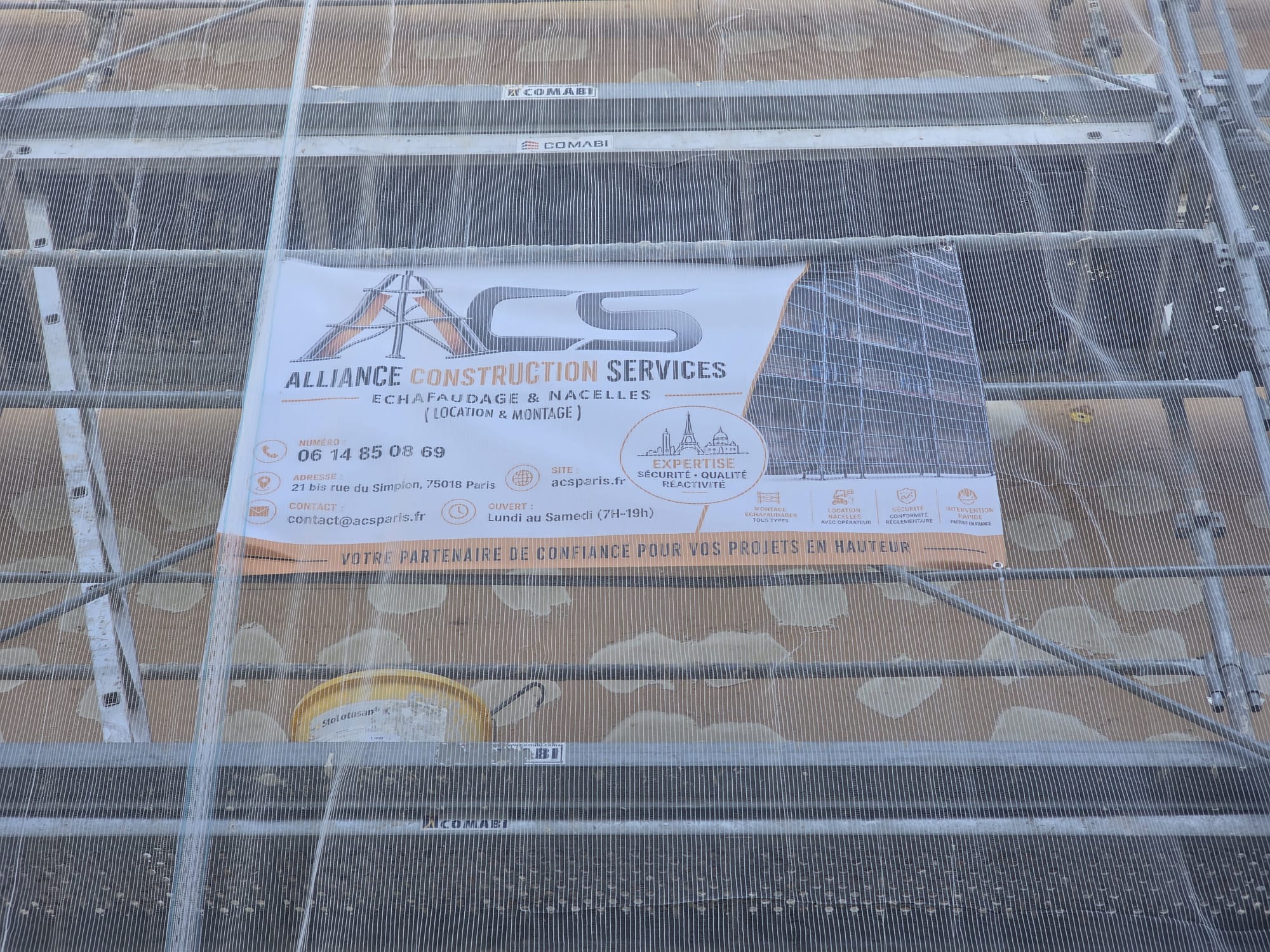 Bannière ACS Alliance Construction Services sur un échafaudage de façade en cours d'isolation