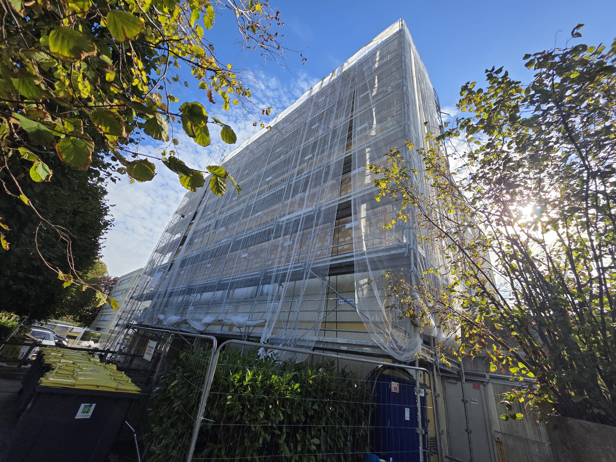 Façade d'immeuble en cours d'isolation sous échafaudage habillé de filets blancs